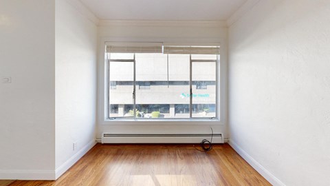 an empty room with a window and wooden floors